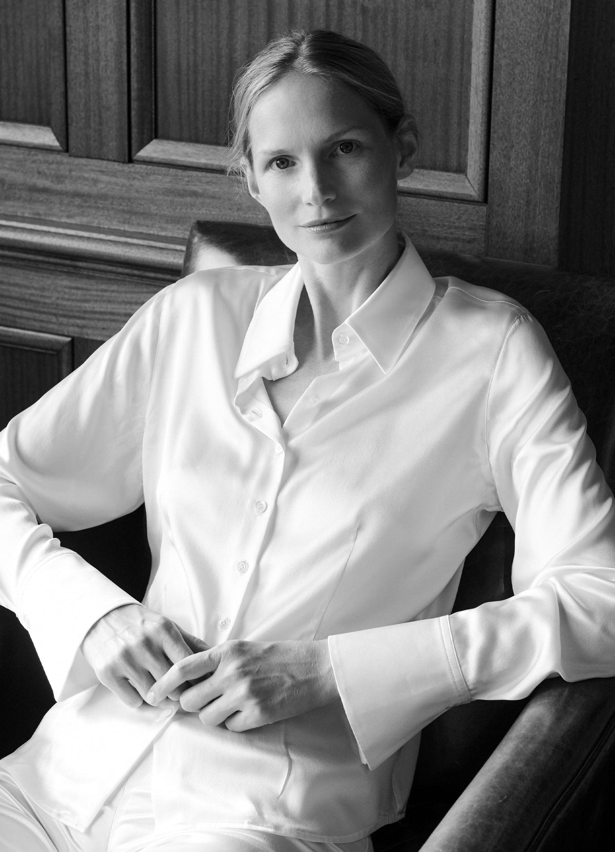 SCHOENBACH white silk blouse worn seated, defined by a clean silhouette and precise tailoring