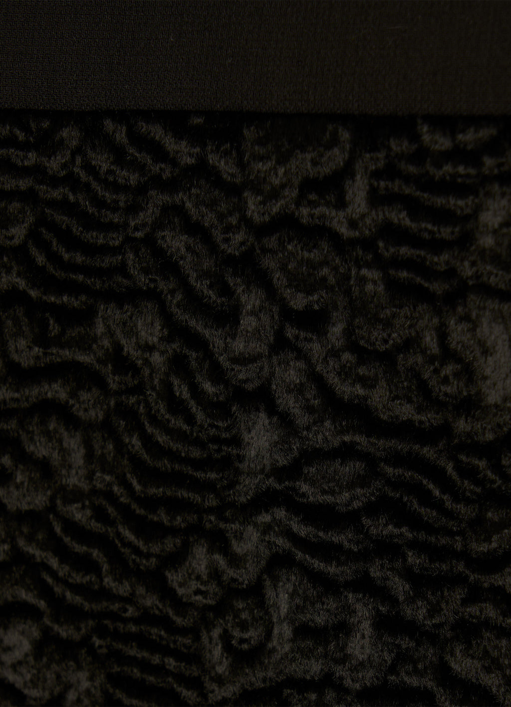 Close-up of textured velvet hem on black skirt