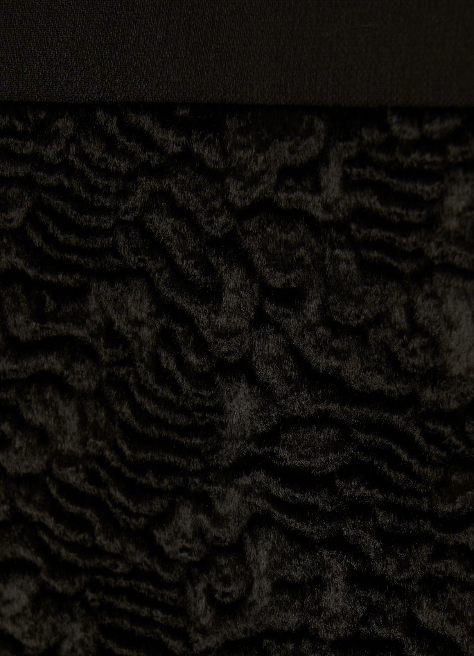 Close-up of textured velvet hem on black skirt