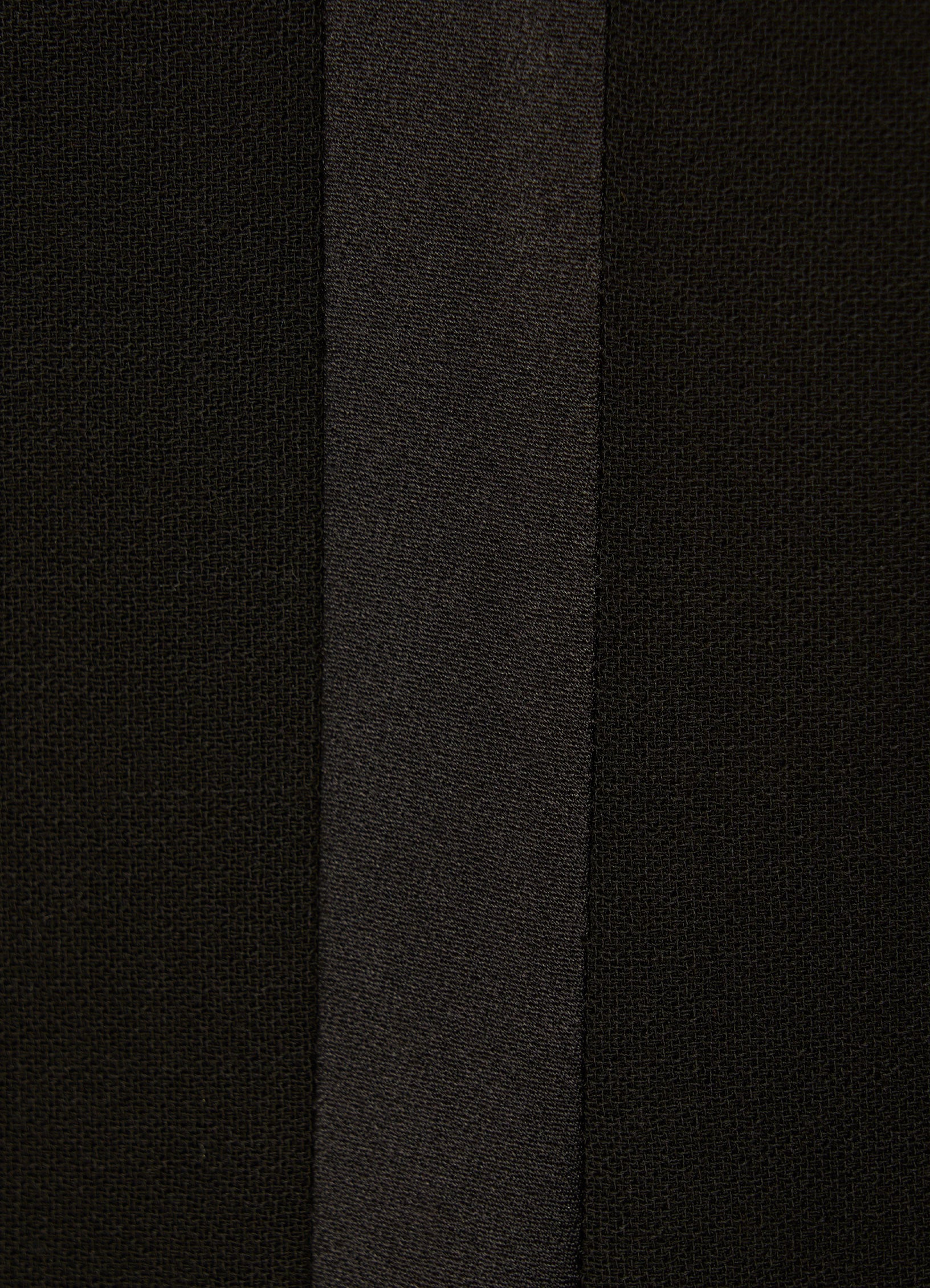 Close-up of black wool smoking trousers with satin side stripe