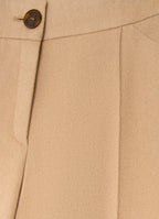 Detail of camel wool-cashmere trousers showing tailored waistband, button fastening and soft structured fabric