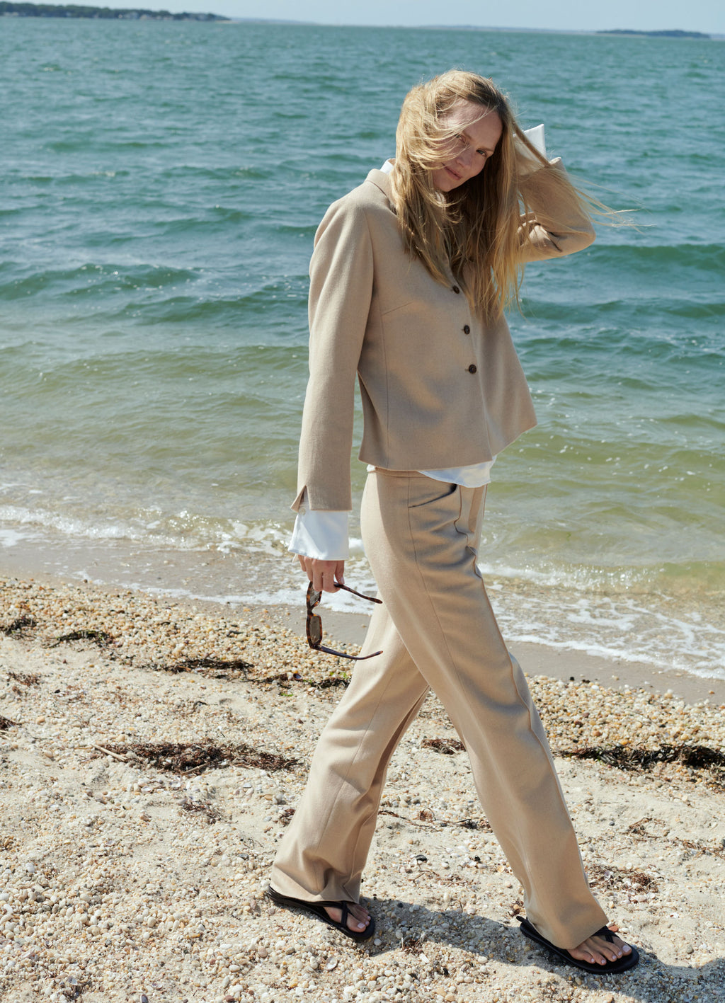 Camel wool-cashmere straight-leg trousers styled with matching jacket in relaxed beach setting