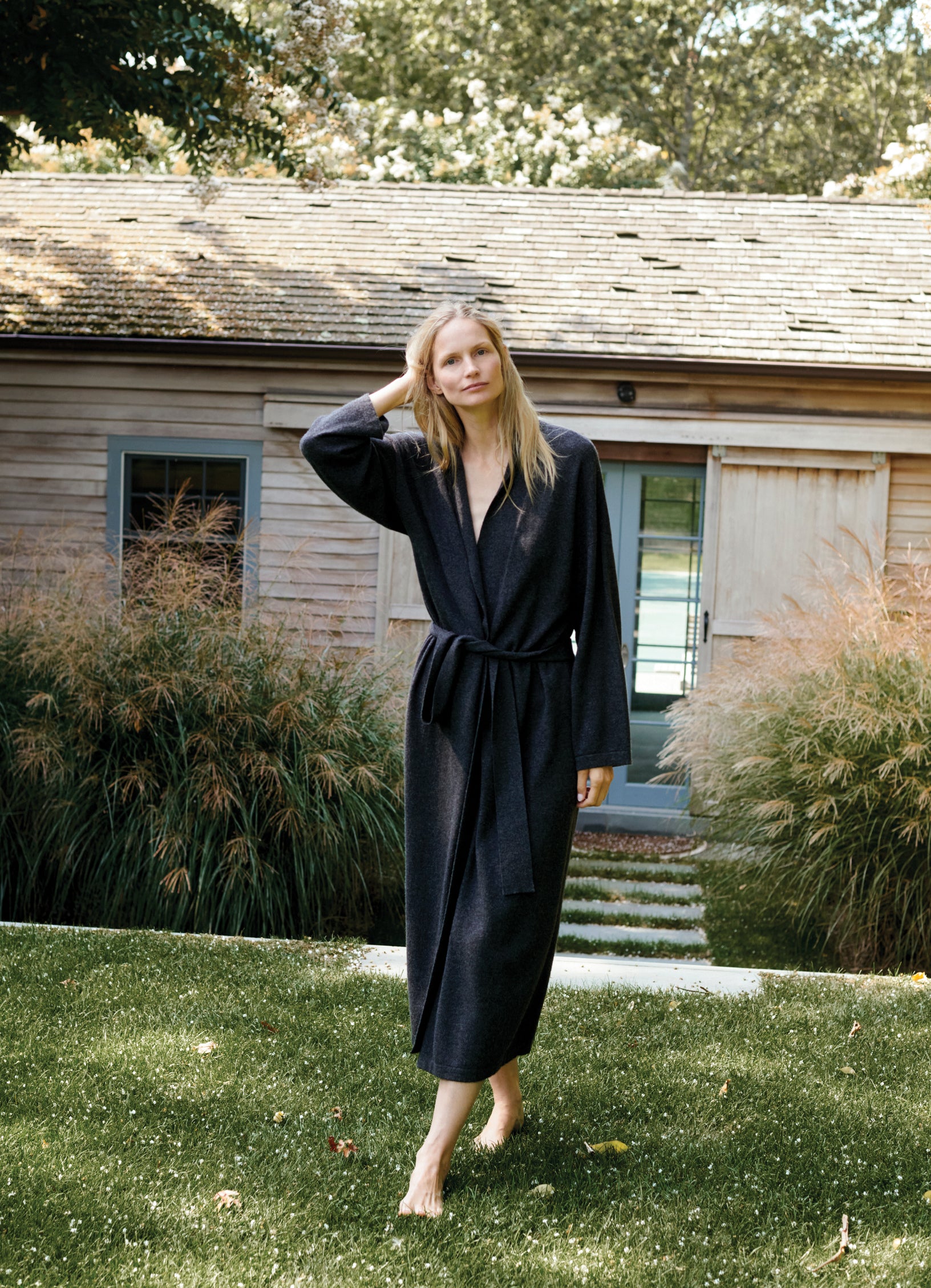 Model Katrin Thormann wearing a long grey cashmere cardigan layered over tonal tailoring in an editorial Hamptons setting.