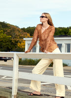 Straight-leg tailored trousers with cuffs styled with a silk blouse in a summer restaurant setting