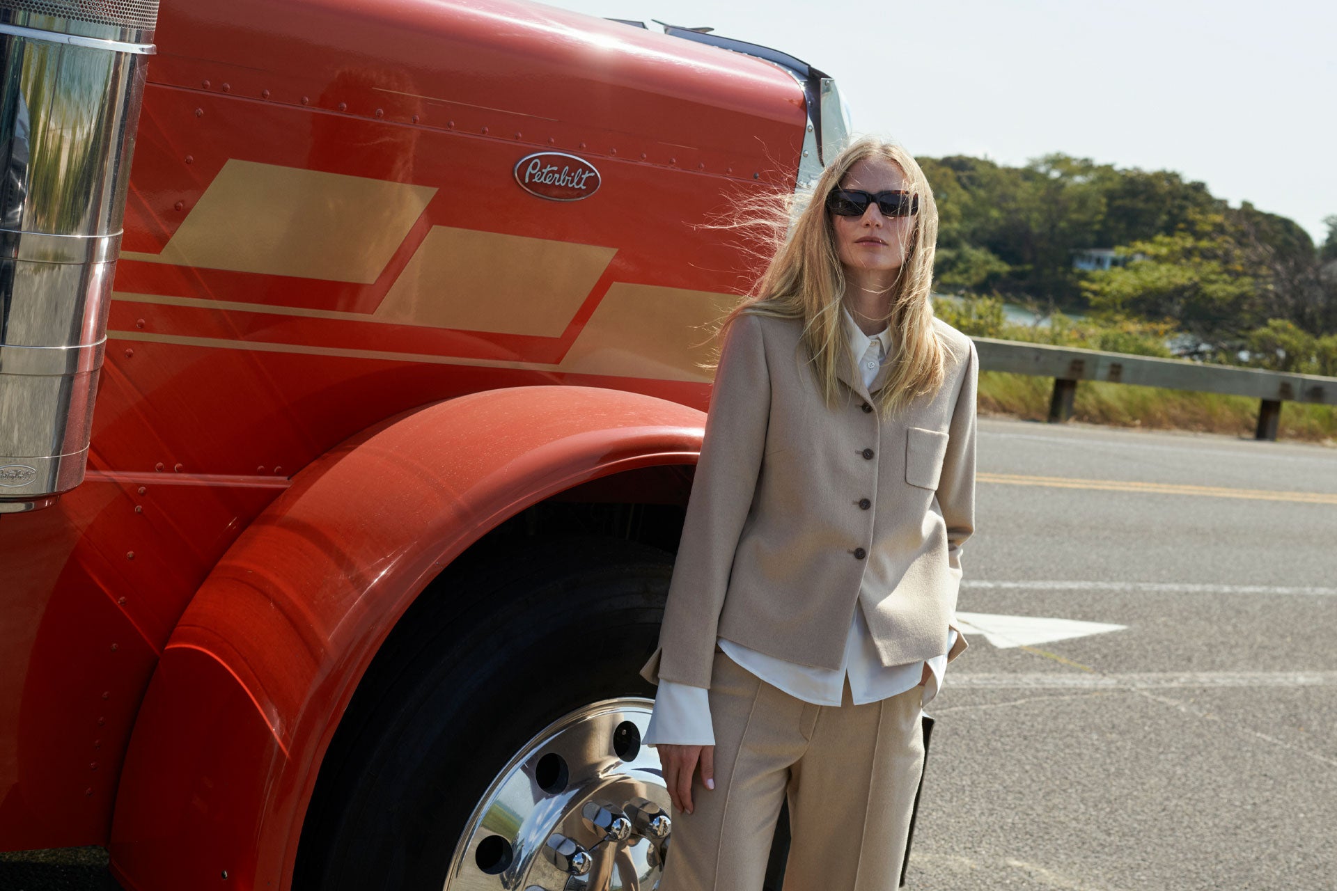 Model Katrin Thormann wearing SCHOENBACH camel tailored suit with a red truck close to Sag Harbour