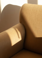 Beige SCHOENBACH Hamptons upholstered chair with sunlight casting shadows on a neutral background