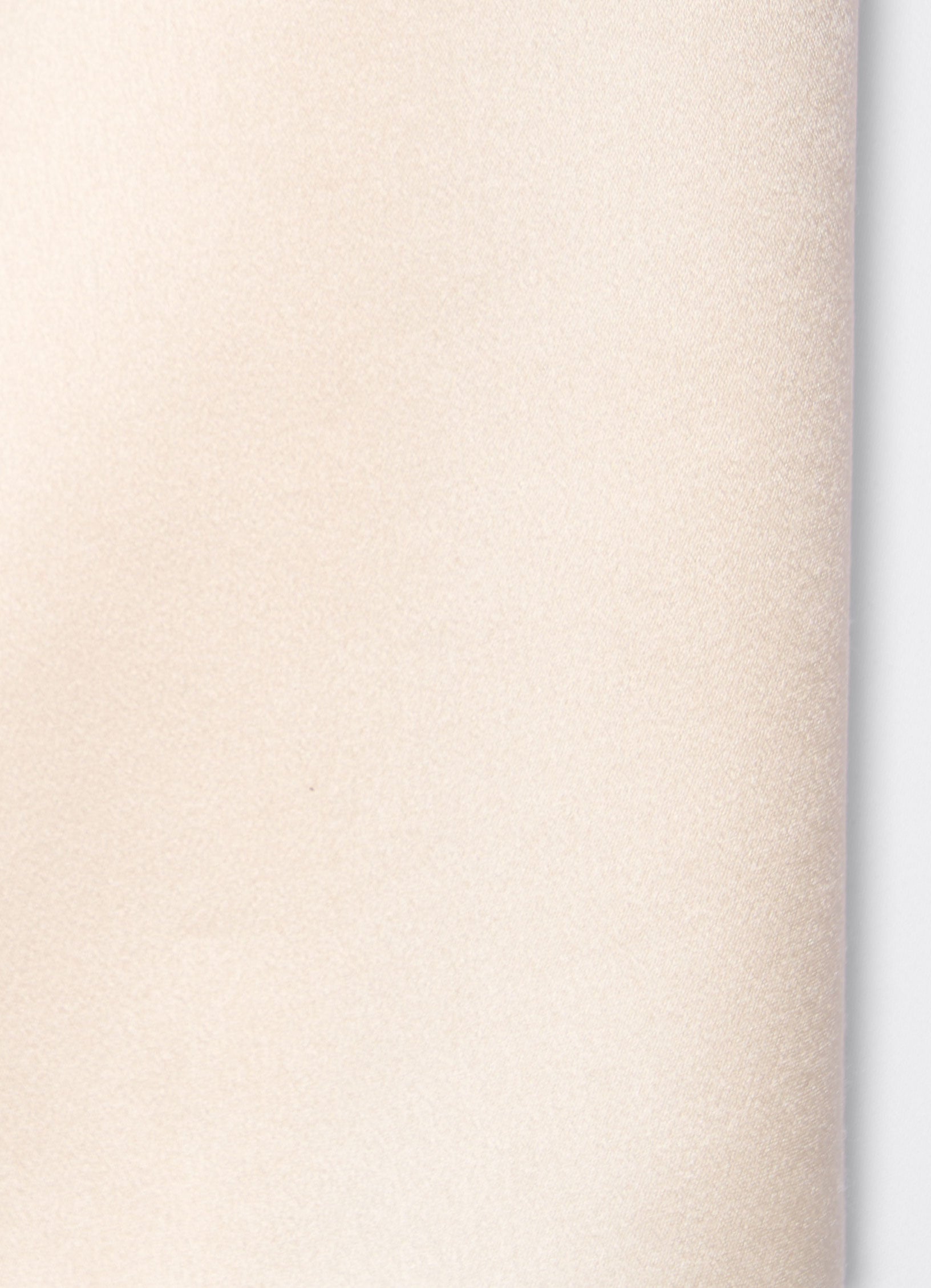 Detail of ivory satin trousers showing soft texture and fluid surface