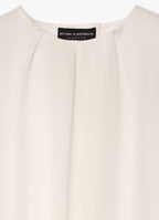 White silk blouse detail with round neckline and front pleat detailing