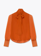 Burnt orange silk blouse with tie neckline, sheer sleeves and elongated cuffs
