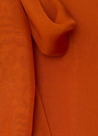 Close-up detail of silk fabric and tie neckline in burnt orange