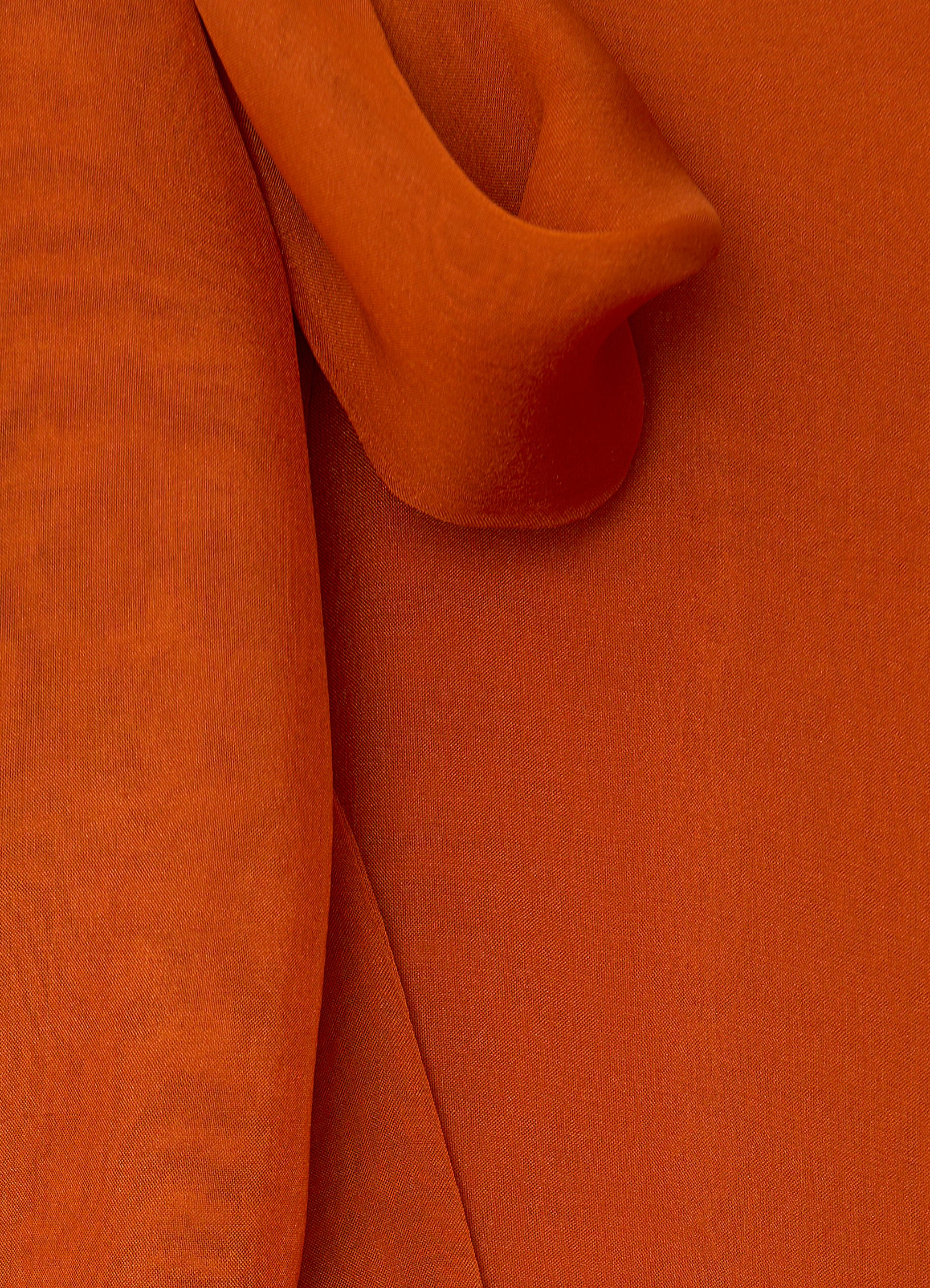 Close-up detail of silk fabric and tie neckline in burnt orange