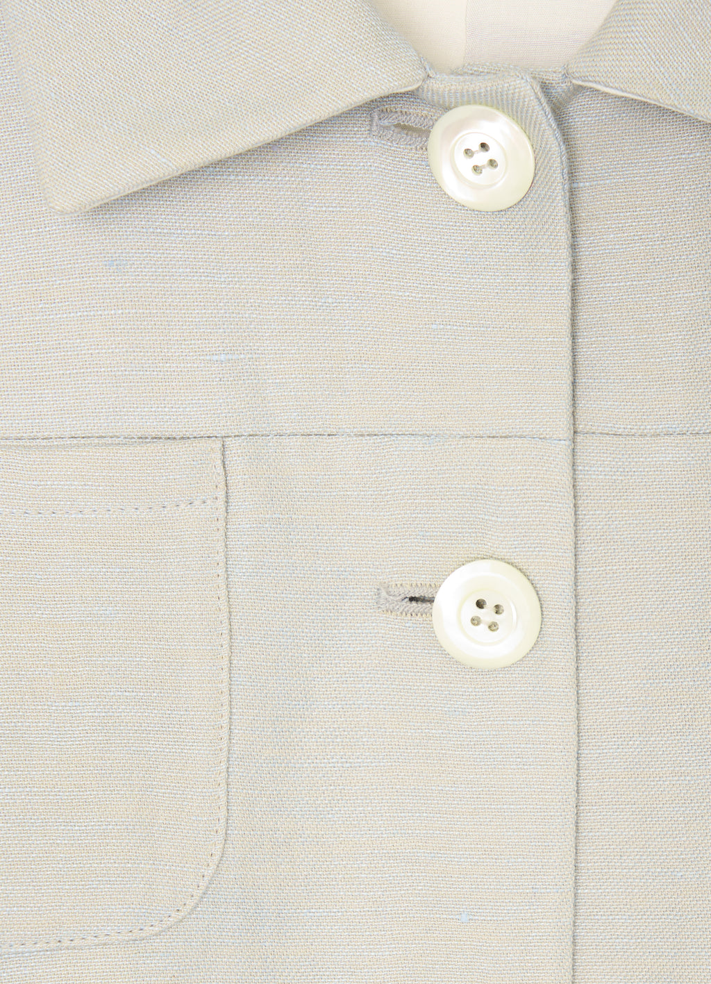 Close-up detail of button fastening and patch pocket on stone tailored jacket