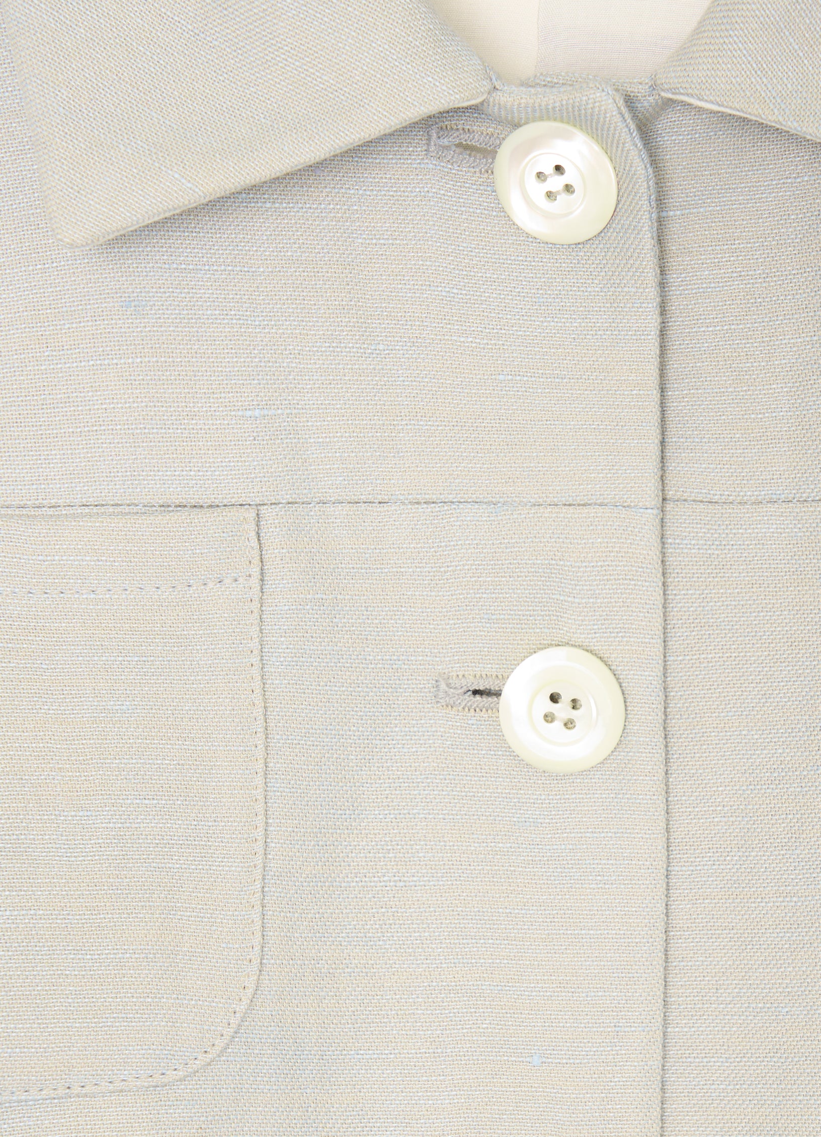 Close-up detail of button fastening and patch pocket on stone tailored jacket