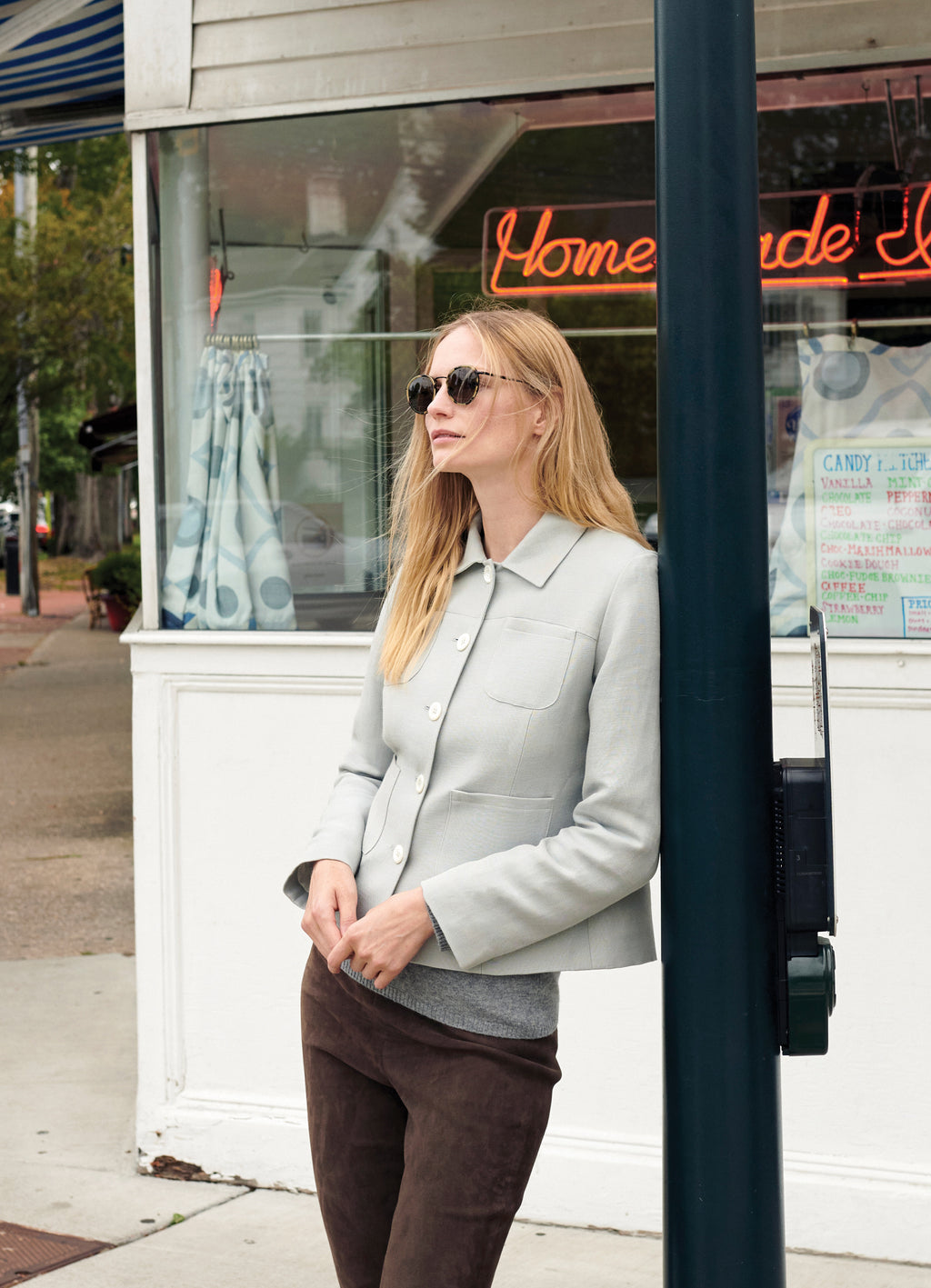 Model Katrin Thormann wearing stone tailored jacket with grey knit and brown leather trousers