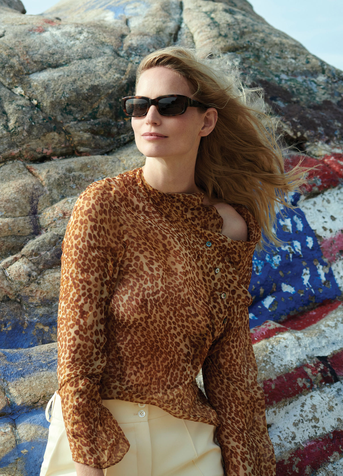 Model Katrin Thormann wearing sheer silk ozelot print blouse styled with ivory tailored trousers
