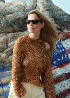 Model Katrin Thormann wearing sheer silk ozelot print blouse styled with ivory tailored trousers