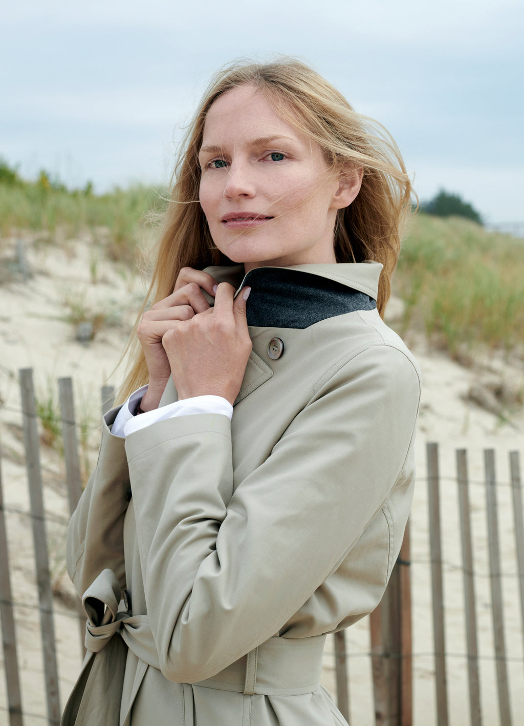 Taupe trench coat worn outdoors with structured collar